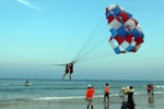 Khách du lịch tham gia trò chơi canô kéo dù tại biển ở Đà Nẵng. (Ảnh: Trần Lê Lâm/TTXVN) 
