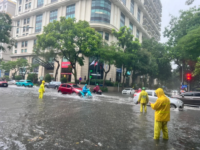 Lực lượng chức năng ứng trực tiêu thoát nước trên đường Lý Thường Kiệt, quận Hoàn Kiếm. (Ảnh: TTXVN phát)