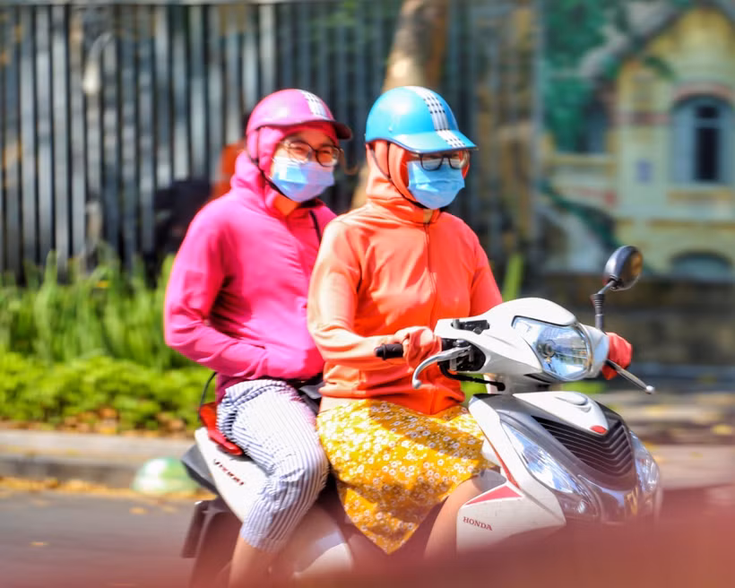Người dân mặc áo chống nắng để tránh sốc nhiệt khi ra đường. (Ảnh: Tuấn Đức/TTXVN)