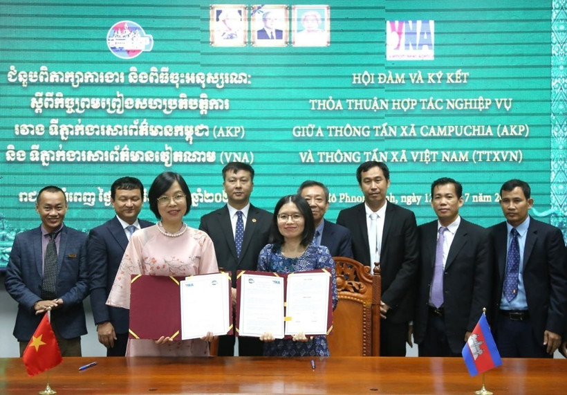 Tổng Giám đốc TTXVN Vũ Việt Trang (bên trái) và Tổng Giám đốc AKP Sokmom Nimul trao đổi thỏa thuận hợp tác nghiệp vụ giai đoạn mới vừa ký kết. (Ảnh: Hoàng Minh/TTXVN)