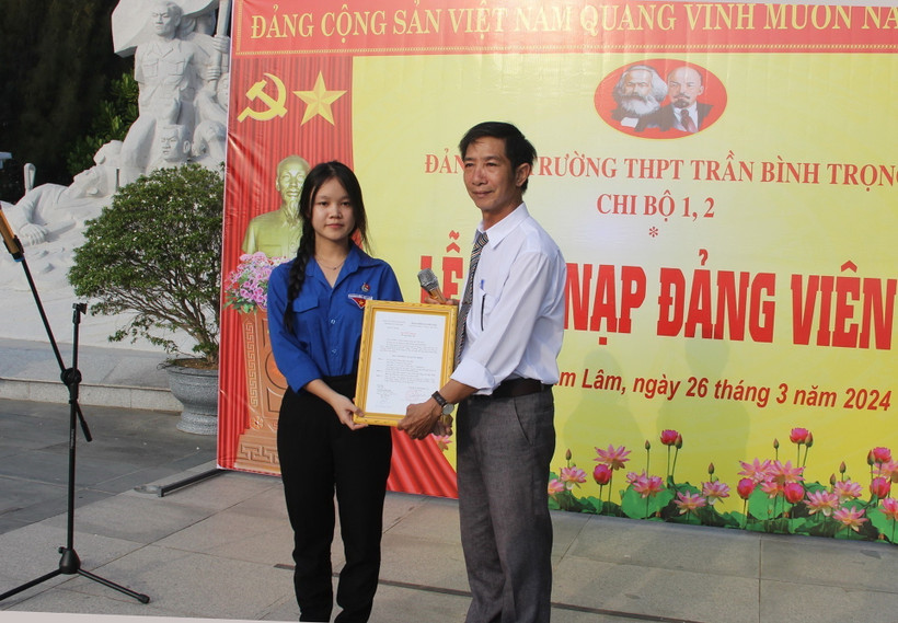 Đại diện Đảng ủy Trường Trung học Phổ thông Trần Bình Trọng, huyện Cam Lâm trao Quyết định kết nạp đảng viên cho quần chúng ưu tú Lâm Uyên Kha. (Ảnh: Phan Sáu/TTXVN)