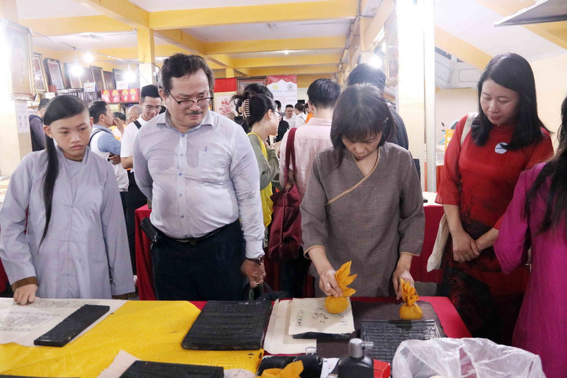 Bạn đọc, người tham quan triển lãm có cơ hội trải nghiệm in tranh, kinh Phật trên mộc bản. (Ảnh: Xuân Khu/TTXVN)