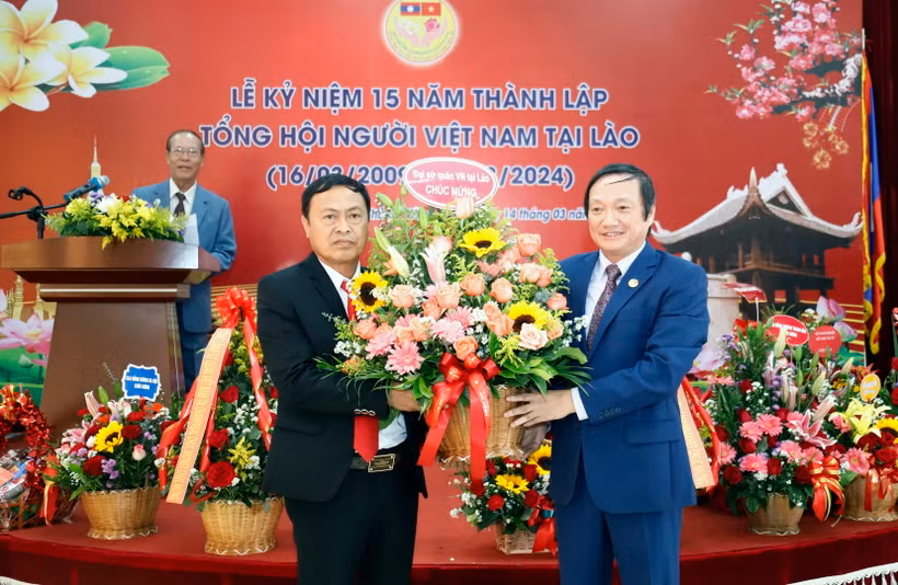 Đại sứ Việt Nam tại Lào Nguyễn Bá Hùng tặng hoa chúc mừng 15 năm thành lập Tổng hội. (Ảnh: Phạm Kiên/TTXVN)