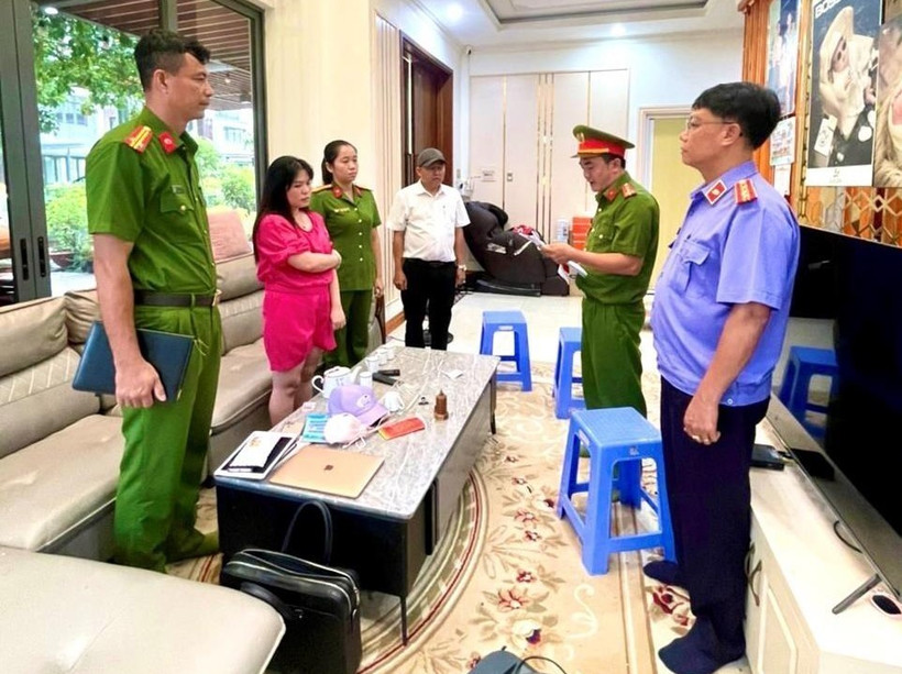 Cơ quan cảnh sát điều tra đọc lệnh khám xét nơi làm việc của Đỗ Thị Thu Trang (áo đỏ). (Ảnh: TTXVN phát)