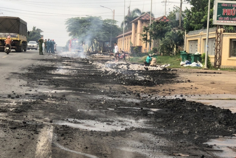 Một khối lượng lớn than bốc cháy trên xe hàng được người dân cào xuống đường dập tắt. (Ảnh: TTXVN phát)