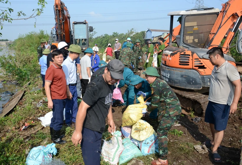 Người dân cùng lực lượng chức năng khắc phục sự cố công trình thủy lợi Ngũ Huyện Khê. (Ảnh: TTXVN phát)