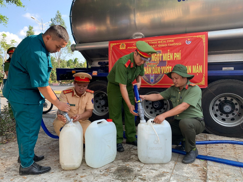 Cán bộ, chiến sỹ Phòng Cảnh sát Giao thông Công an tỉnh Bến Tre cùng các đơn vị liên quan cấp nước ngọt cho người dân. (Ảnh: TTXVN phát)
