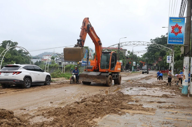 Thành phố Hà Giang huy động các lực lượng và phương tiện dọn dẹp tuyến đường bị ngập sâu. (Ảnh: TTXVN phát)