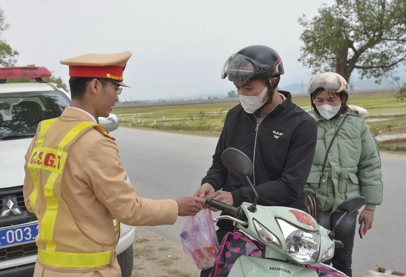 Lực lượng Cảnh sát Giao thông Công an tỉnh Điện Biên phát quà cho người dân trên đường về quê ăn Tết năm 2023. (Ảnh: Xuân Tư/TTXVN)