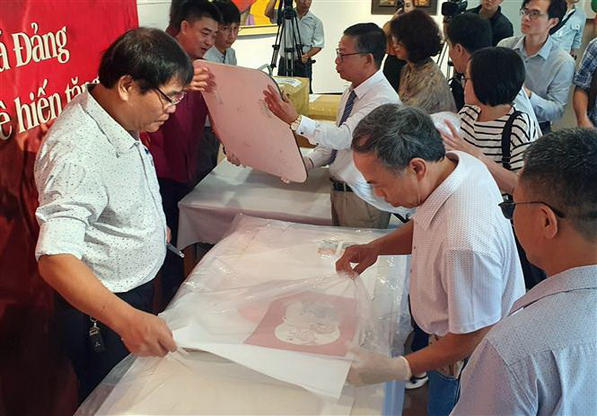 Mở niêm phong các hiện vật được hiến tặng. (Ảnh: Trần Lê Lâm/TTXVN)