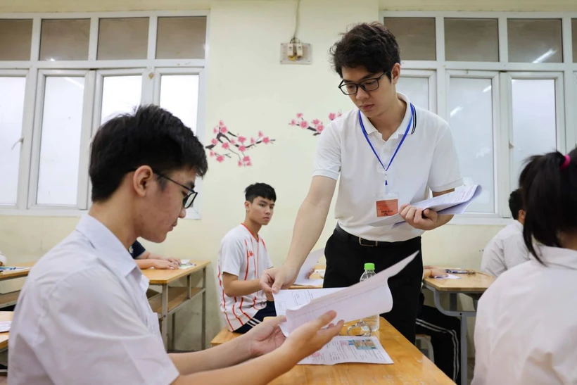 Giám thị phát giấy thi cho thí sinh dự thi môn Toán tại điểm thi Trường Trung học Phổ thông Lê Quý Đôn, quận Đống Đa. (Ảnh: Thanh Tùng/TTXVN)