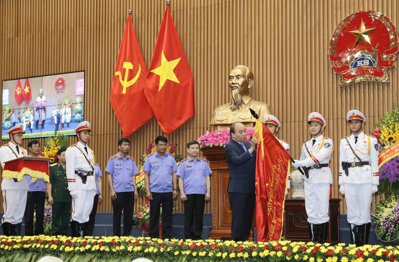 Thủ tướng Nguyễn Xuân Phúc gắn Huân chương Hồ Chí Minh lên lá cờ truyền thống của Viện Kiểm sát Nhân dân Tối cao. (Ảnh: Doãn Tấn/TTXVN)