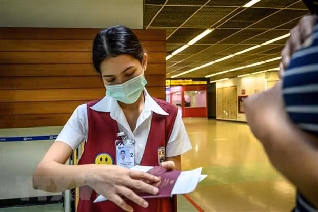 Nhân viên kiểm tra hộ chiếu của một hành khách tại sân bay Don Mueang ở Bangkok, Thái Lan, ngày 21/1/2020. (Ảnh: AFP/TTXVN)