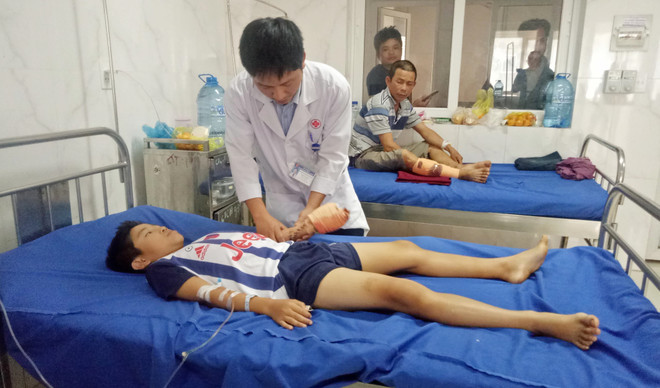 Bác sĩ kiểm tra vết thương và theo dõi cử động bàn tay trái của bệnh nhân. (Ảnh: TTXVN phát) Đắk Lắk: Bé trai bị dập nát tay do dùng điện thoại đang sạc pin ảnh 1