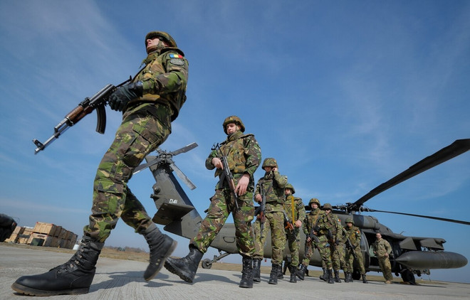 Binh sỹ Romania đứng cạnh trực thăng Black Hawk của quân đội Mỹ. (Ảnh: AP) Mỹ tập trận chung với Romania, cam kết đảm bảo an ninh ở Biển Đen ảnh 1