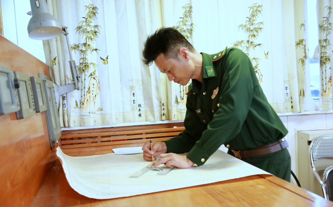 Thiếu tá Khúc Ngọc Minh tác nghiệp hải đồ thực hiện nhiệm vụ chuyên môn. (Ảnh: Minh Thu/TTXVN) ttxvn_thuyen truong bo doi bien phong 2.jpg
