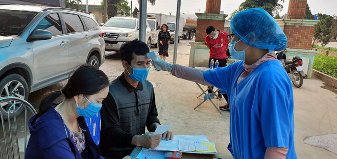 Cán bộ y tế tiến hành đo thân nhiệt và kê khai y tế tại chốt kiểm soát Covid-19 cầu Vàng Chua, thị xã Đông Triều, tỉnh Quảng Ninh. (Ảnh: Đức Hiếu/TTXVN) Quảng Ninh: Chống dịch COVID-19, các thủ tục hành chính vẫn thông suốt ảnh 1
