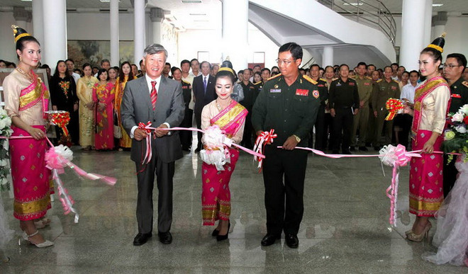 Đại sứ Nguyễn Mạnh Hùng và Trung tướng Souvon cắt băng khai mạc triển lãm ảnh về Quân tình nguyện Việt Nam. (Nguồn: Hoàng Chương/Vietnam+) Kỷ niệm 65 năm truyền thống quân tình nguyện Việt Nam tại Lào ảnh 1