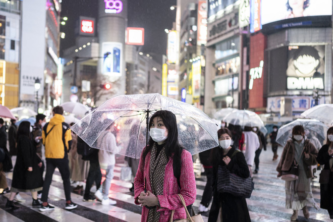 Người dân đeo khẩu trang phòng dịch COVID-19 khi di chuyển trên đường phố ở Tokyo, Nhật Bản ngày 5/3/2021. (Ảnh: AFP/TTXVN) COVID-19: Nhật Bản nới lỏng quy định sau khi dỡ bỏ tình trạng khẩn cấp ảnh 1