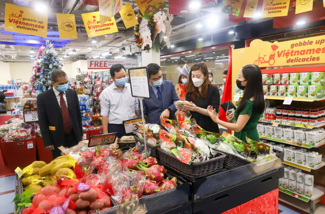 Bà Goh Tsu Ching (thứ 2, từ phải sang), Giám đốc cung ứng quốc tế FairPrice, giới thiệu các mặt hàng trưng bày tại Tuần lễ hàng Việt Nam. (Ảnh: Lê Dương/TTXVN) Khai mạc tuần lễ hàng Việt Nam 2021 tại hệ thống siêu thị Singapore ảnh 1
