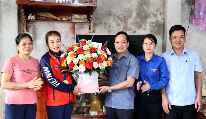 Lãnh đạo Ủy ban Nhân dân huyện Yên Lập tặng hoa và quà chúc mừng vận động viên Triệu Thị Phương Thủy, đạt Huy chương Vàng SEA Games 32. (Ảnh: Trung Kiên/TTXVN) SEA Games 32: Cô gái dân tộc Dao mang Huy chương Vàng về cho Tổ quốc ảnh 3