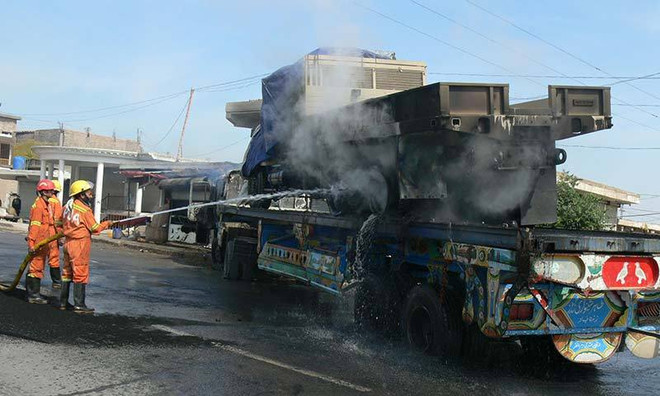 Lính cứu hỏa Pakistan phun nước vào chiếc xe tải đang cháy chuyên chở xe quân sự của NATO. (Ảnh: AFP) Pakistan phá âm mưu tấn công trạm hậu cần của NATO ảnh 1