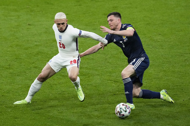 Tiền đạo đội tuyển Anh Phil Foden (trái) tranh bóng với hậu vệ Scotland Andrew Robertson. (Ảnh: AFP/TTXVN) Cầu thủ trẻ Phil Foden bênh vực huấn luyện viên Gareth Southgate ảnh 1