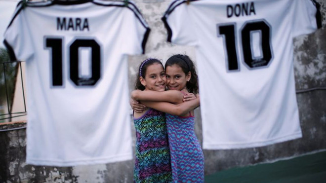 Hai bé gái song sinh Mara và Dona cùng chiếc áo số 10 của thần tượng Diego Maradona. (Ảnh: Reuters) Tinh thần "cháy hết mình" của Maradona còn mãi trong lòng người hâm mộ ảnh 2