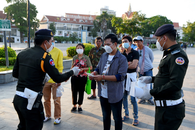 Cảnh sát phát khẩu trang cho người dân để phòng dịch COVID-19 tại Phnom Penh, Campuchia ngày 12/11/2020. (Ảnh: AFP/TTXVN) COVID-19: Campuchia phạt nặng trường hợp vi phạm quy định phòng dịch ảnh 1
