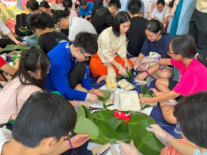 Các bạn trẻ thích thú với hoạt động gói bánh chưng truyền thống. (Ảnh: TTXVN) ttxvn_tet tam tinh singapore 2.jpg