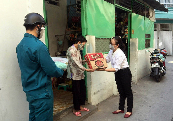 Đại diện các địa phương của Thành phố Hồ Chí Minh hỗ trợ cho người dân gặp khó khăn tại quận Bình Thạnh. (Ảnh: Tiến Lực/TTXVN) TP. HCM chi hơn 14 tỷ đồng hỗ trợ người bán vé số gặp khó khăn ảnh 1