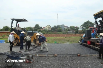 Nhà thầu thi công thảm nhựa nền đường một dự án đường bộ cao tốc. (Ảnh: Việt Hùng/Vietnam+)
