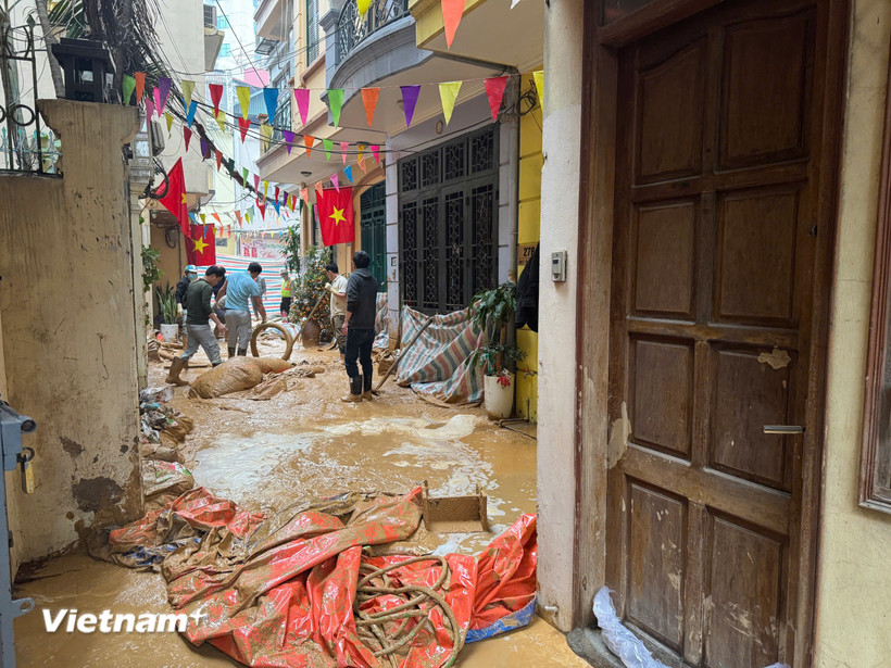 Bùn đất phun trào lên cống và được các lực lượng chức năng xử lý hút, thu dọn. (Ảnh: Minh Hiếu/Vietnam+) 