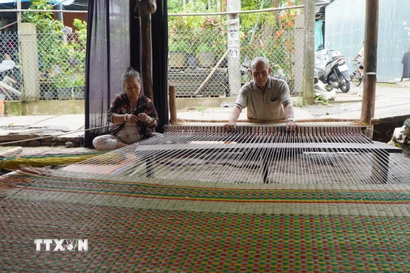 Gia đình ông Huỳnh Văn Chiến là một trong số ít hộ dân ở làng chiếu Định Yên còn dệt chiếu thủ công để giới thiệu nghề truyền thống với khách du lịch. (Ảnh: Nhựt AnTTXVN)