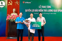Đại diện Liên đoàn Lao động (bên trái) và đại diện công ty Cao Su Quảng Trị (bên phải) trao bảo hiểm cho người lao động. (Ảnh: Vietnam+)