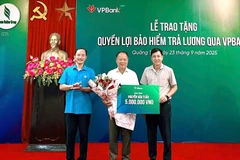 Đại diện Liên đoàn Lao động (bên trái) và đại diện công ty Cao Su Quảng Trị (bên phải) trao bảo hiểm cho người lao động. (Ảnh: Vietnam+)