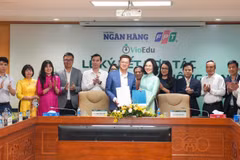 Đại diện Thời báo Ngân hàng và đại diện Tập đoàn FPT trao biên bản hợp tác. (Ảnh: Vietnam+)
