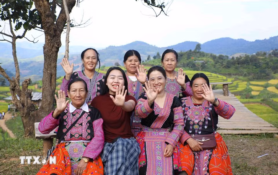 Du khách và đồng bào dân tộc Mông vùng cao mời gọi du khách đến tham quan ruộng bậc thang Pu Nhi. (Ảnh: Xuân Tư/TTXVN)