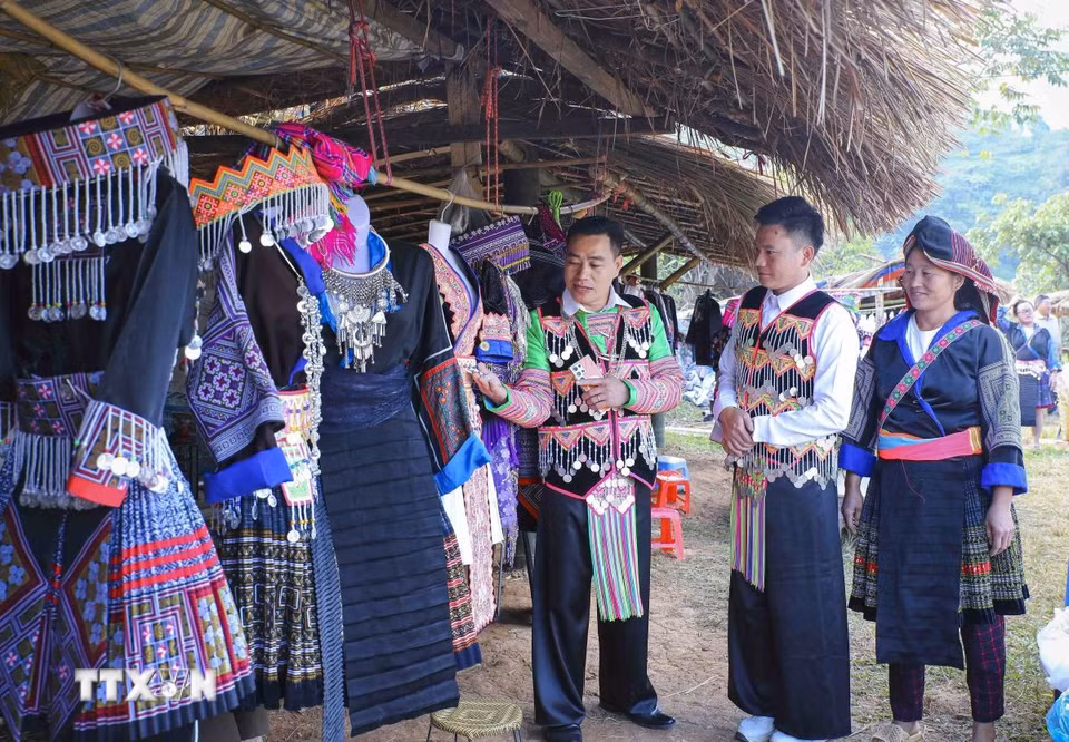 Đồng bào dân tộc Mông giới thiệu, cho thuê trang phục tại khu vực ruộng bậc thang Pu Nhi. (Ảnh: Xuân Tư/TTXVN)