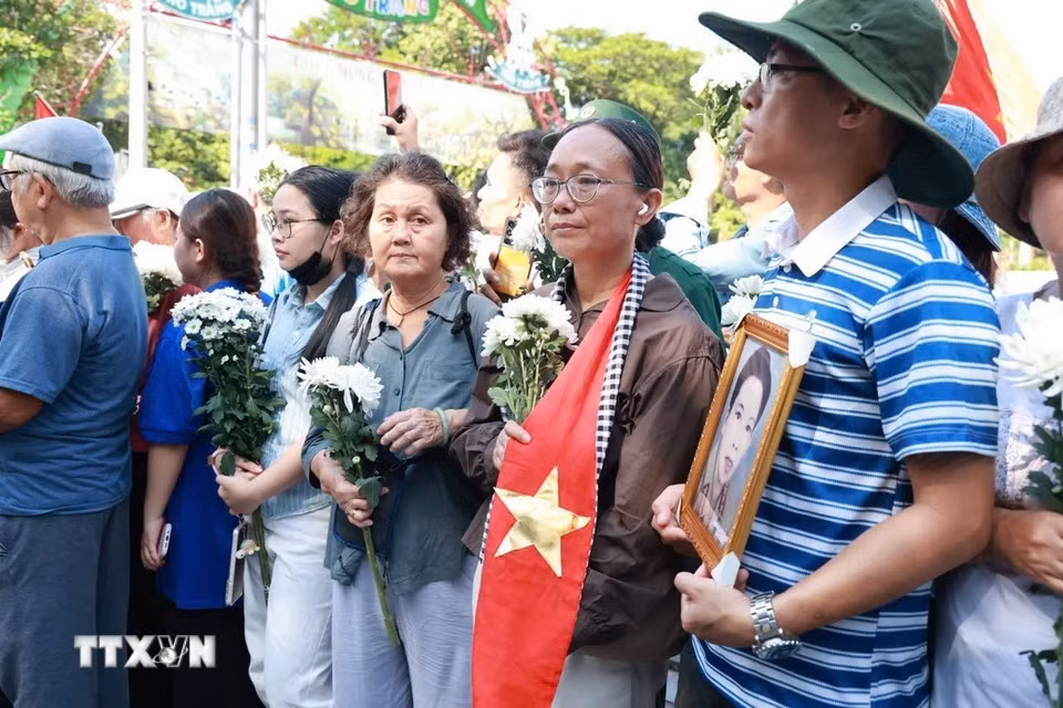 Người dân cầm hoa và di ảnh chờ tiễn đoàn xe đưa liệt sỹ. (Ảnh: Mạnh Minh/TTXVN)