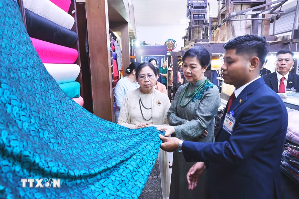 Phu nhân Ngô Phương Ly và Phu nhân Kyu Kyu Hla tham quan khu trưng bày sản phẩm lụa truyền thống và giới thiệu các sản phẩm đặc sắc của làng nghề. (Ảnh: Minh Đức/TTXVN)