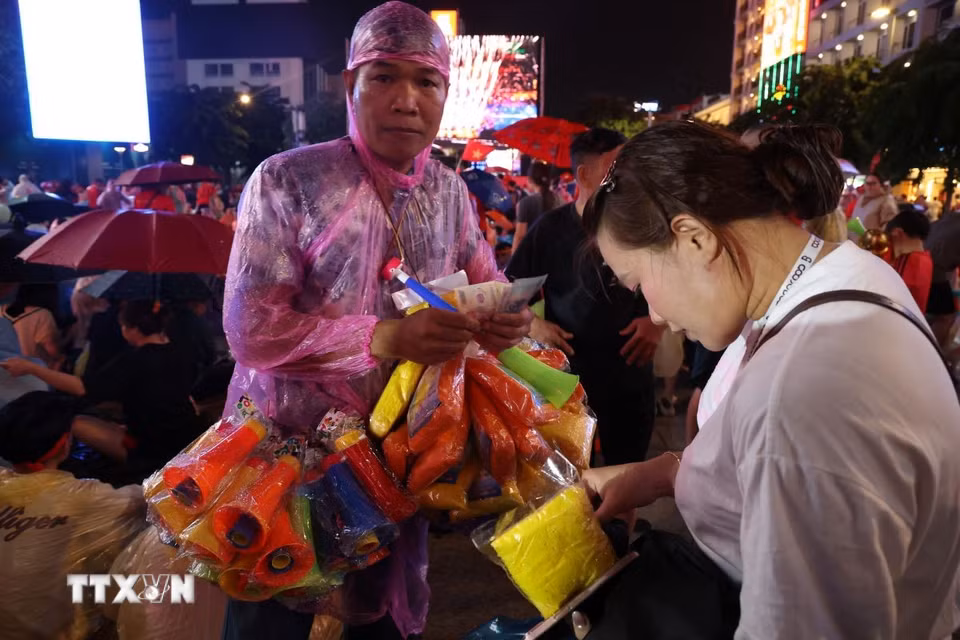 Áo mưa và kèn đắt hàng trước trận chung kết lượt về Asian Cup giữa Việt Nam và Thái Lan trên phố đi bộ Nguyễn Huệ. (Ảnh: Hồng Đạt/TTXVN)