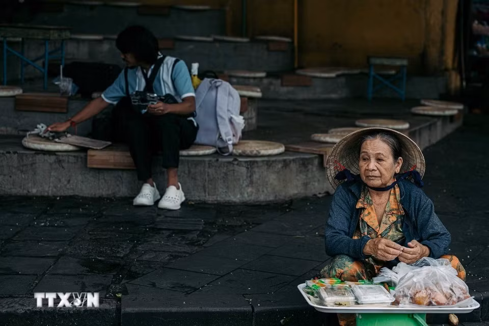 Một người phụ nữ lớn tuổi bán hàng bên hiên phố cổ. Chính những sinh hoạt bình dị của cư dân đã khiến Hội An không chỉ là quần thể kiến trúc được bảo tồn mà còn là một di sản sống được tiếp nối qua nhiều thế hệ. (Ảnh: Phạm Tuấn Anh/TTXVN)