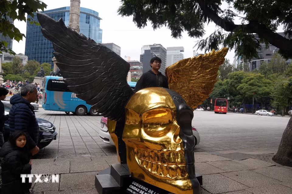 Người dân chụp ảnh cùng mô hình đầu lâu được cách điệu đôi cánh thiên thần. (Ảnh: Phi Hùng/TTXVN)