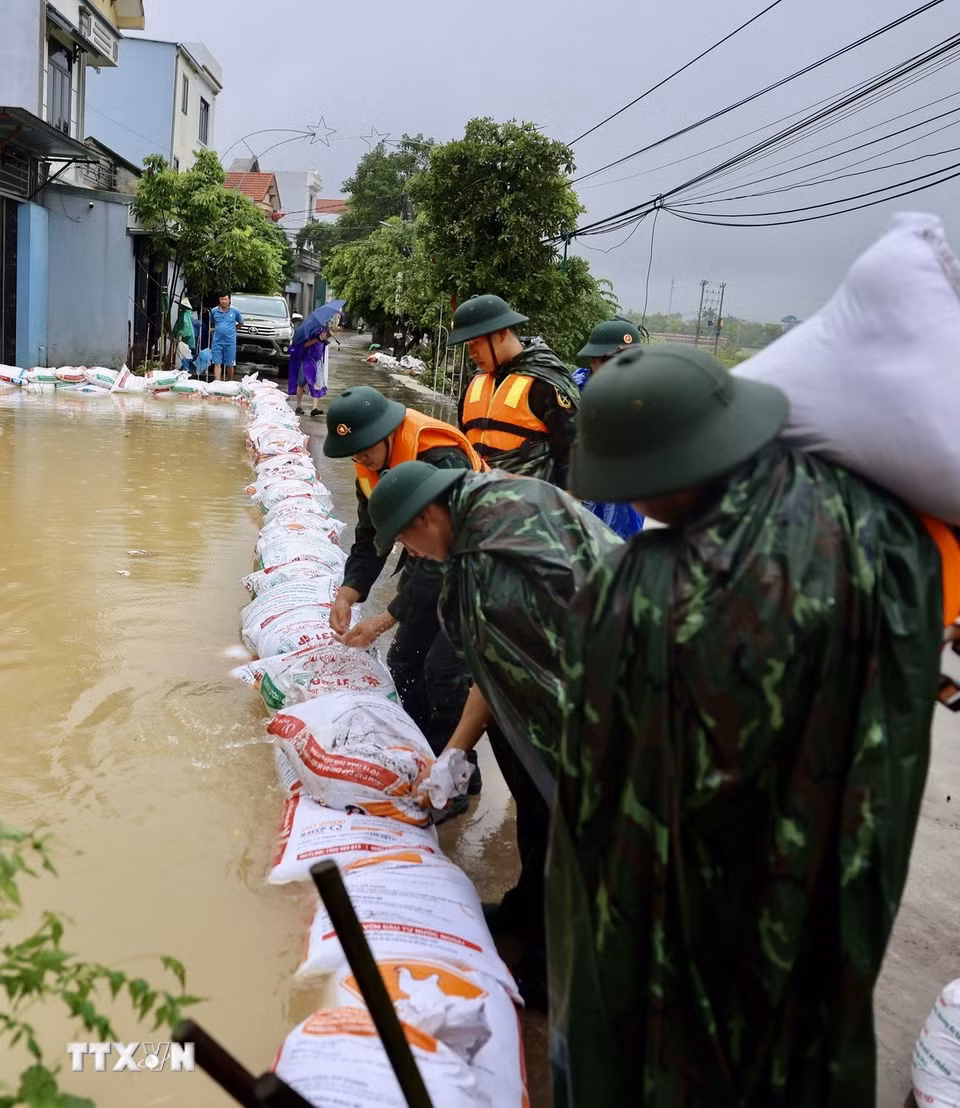 Lực lượng bộ đội hỗ trợ đắp đê bao ngăn nước khu dân cư ven sông Bùi. (Ảnh: Nhật Anh/TTXVN)