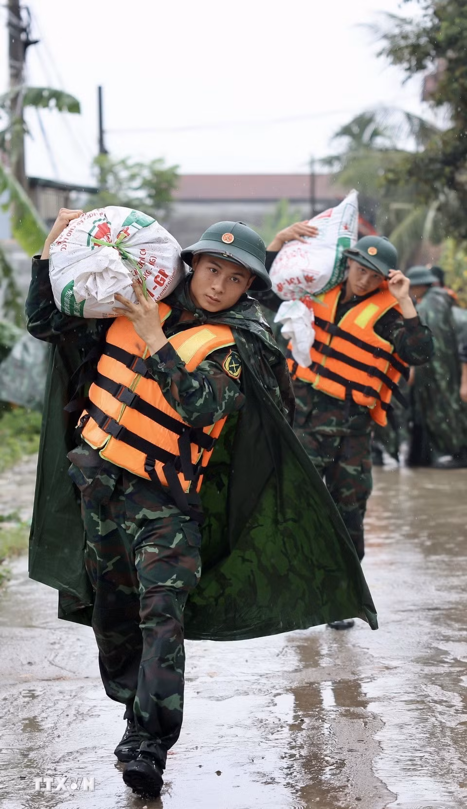 Lực lượng bộ đội hỗ trợ đắp đê bao ngăn nước khu dân cư ven sông Bùi. (Ảnh: Nhật Anh/TTXVN)