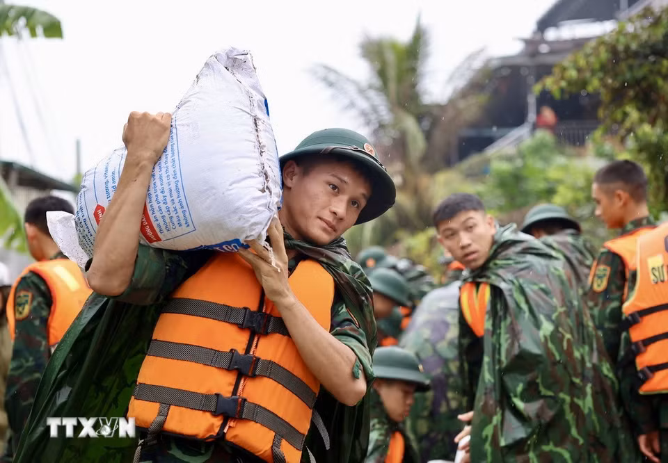 Lực lượng bộ đội hỗ trợ đắp đê bao ngăn nước khu dân cư ven sông Bùi. (Ảnh: Nhật Anh/TTXVN)