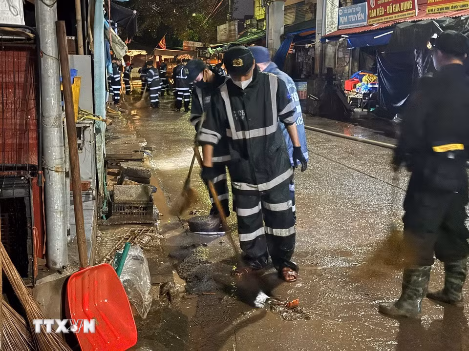 Các chiến sỹ dọn dẹp hệ thống thoát nước của chợ. (Ảnh: Tiến Vĩnh/TTXVN)