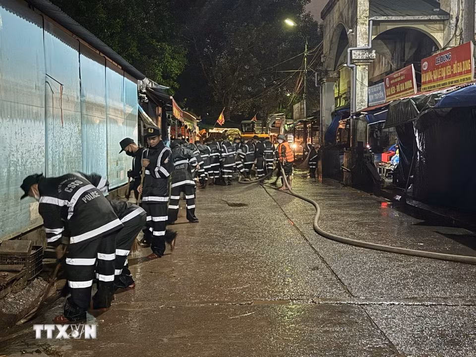 Lực lượng chức năng tổ chức dọn dẹp các lối đi trong chợ. (Ảnh: Tiến Vĩnh/TTXVN)