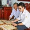 Em Trần Xuân Đam và bố giới thiệu những tấm bằng khen đã đạt được trong quá trình học tập. (Ảnh: Công Luật/TTXVN)